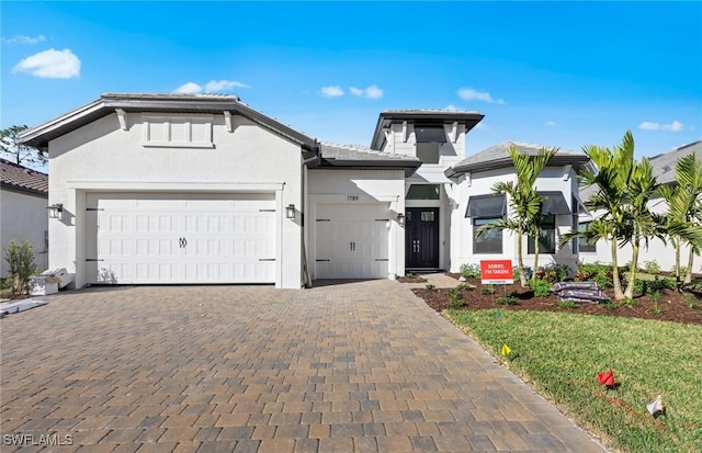 1825 Verada Ct, Naples, FL 34120 - view of front of house featuring decorative driveway, a garage, stucco siding, and a tiled roof