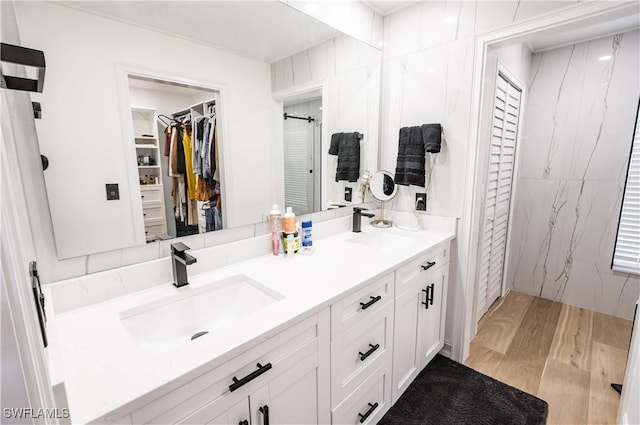 4924 20th Pl SW, Naples, FL 34116 - bathroom featuring wood finished floors, double vanity, a spacious closet, and a shower with shower door