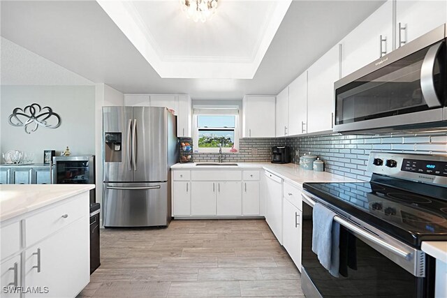 2 Pirates Ln Unit 24B, Punta Gorda, FL 33955 - kitchen featuring stainless steel appliances, a sink, a raised ceiling, light countertops, and decorative backsplash