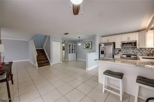 1464 Park Shore Cir Unit 2, Fort Myers, FL 33901 - kitchen with appliances with stainless steel finishes, light stone countertops, a peninsula, and white cabinetry