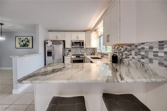1464 Park Shore Cir Unit 2, Fort Myers, FL 33901 - kitchen featuring appliances with stainless steel finishes, a peninsula, light tile patterned floors, light stone countertops, and a sink