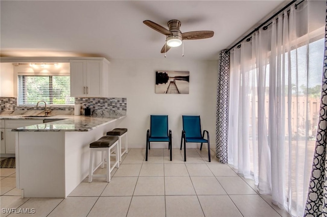 1464 Park Shore Cir Unit 2, Fort Myers, FL 33901 - kitchen with a sink, backsplash, white cabinetry, a kitchen breakfast bar, and ceiling fan