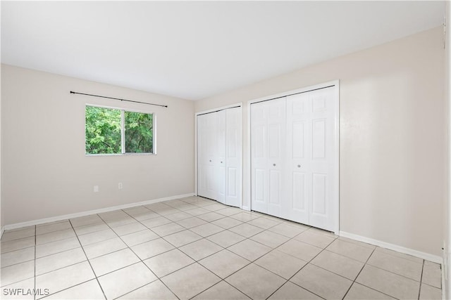 209 Meadow Rd, Lehigh Acres, FL 33973 - unfurnished bedroom featuring two closets, baseboards, and light tile patterned floors