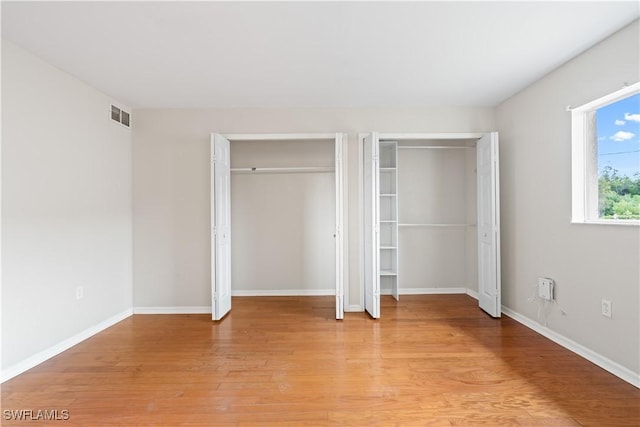 209 Meadow Rd, Lehigh Acres, FL 33973 - unfurnished bedroom featuring two closets, light wood-style flooring, and baseboards