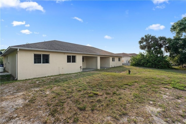 209 Meadow Rd, Lehigh Acres, FL 33973 - back of property with stucco siding and a yard