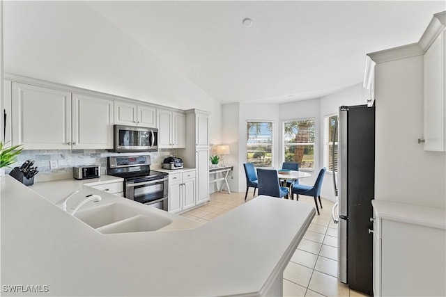 20051 Seagrove St Unit 1206, Estero, FL 33928 - kitchen featuring stainless steel appliances, light tile patterned floors, backsplash, vaulted ceiling, and light countertops