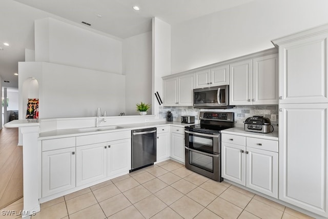 20051 Seagrove St Unit 1206, Estero, FL 33928 - kitchen featuring appliances with stainless steel finishes, a sink, a peninsula, light countertops, and backsplash