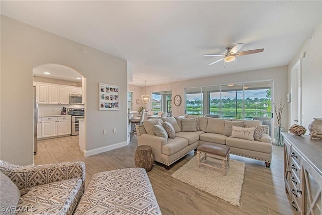 10105 Valiant Ct Unit 101, Miromar Lakes, FL 33913 - living room featuring a ceiling fan, arched walkways, light wood-style floors, and baseboards