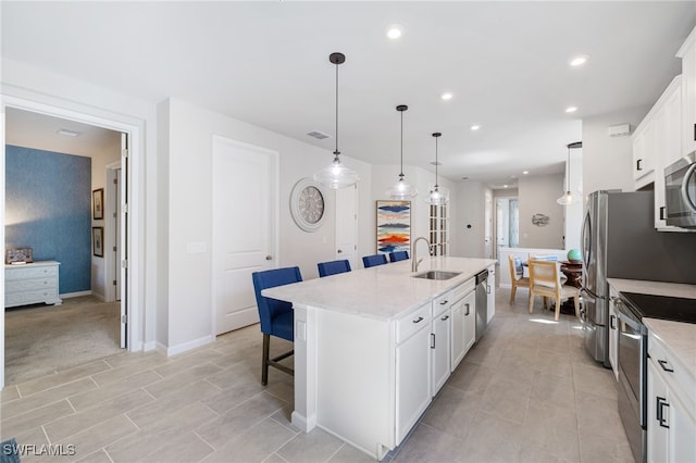 4665 Arboretum Cir Unit 101, Naples, FL 34112 - kitchen featuring appliances with stainless steel finishes, a sink, a kitchen breakfast bar, a kitchen island with sink, and white cabinetry