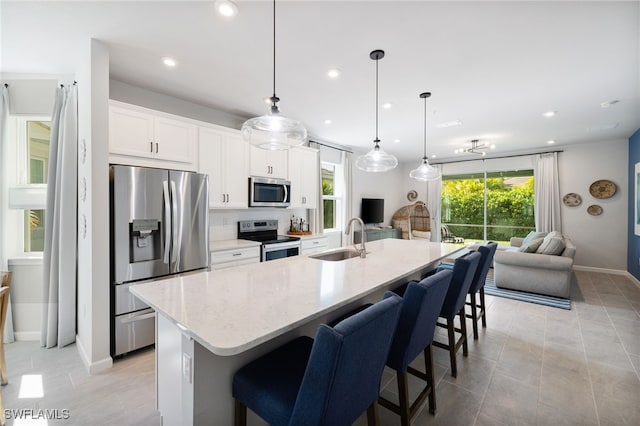 4665 Arboretum Cir Unit 101, Naples, FL 34112 - kitchen with stainless steel appliances, a sink, open floor plan, a kitchen island with sink, and a kitchen breakfast bar