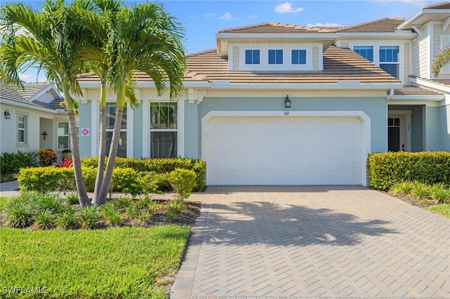 4665 Arboretum Cir Unit 101, Naples, FL 34112 - view of front of home featuring stucco siding, a tile roof, and decorative driveway