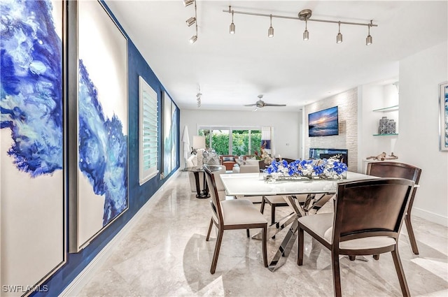 786 109th Ave N, Naples, FL 34108 - dining room featuring a fireplace, rail lighting, a ceiling fan, and baseboards