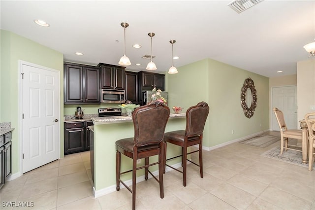 8570 Evernia Ct Unit 101, Estero, FL 34135 - kitchen with appliances with stainless steel finishes, light tile patterned floors, a breakfast bar, recessed lighting, and baseboards