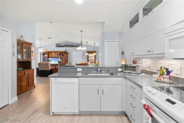923 SW 4th Pl, Cape Coral, FL 33991 - kitchen featuring white appliances, a peninsula, a sink, white cabinets, and lofted ceiling