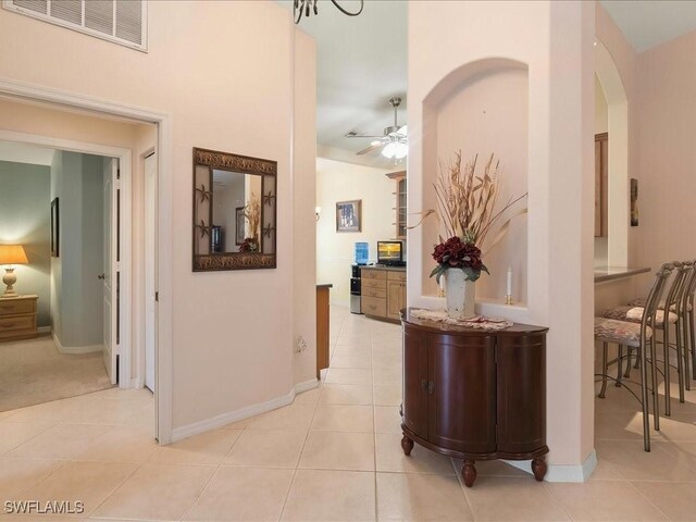 15137 Cortona Way, Naples, FL 34120 - hall featuring light tile patterned floors, arched walkways, and baseboards