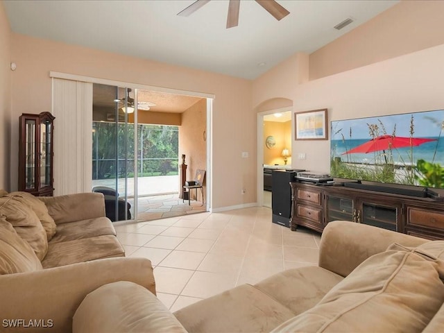 15137 Cortona Way, Naples, FL 34120 - living room featuring a ceiling fan, arched walkways, vaulted ceiling, light tile patterned flooring, and baseboards