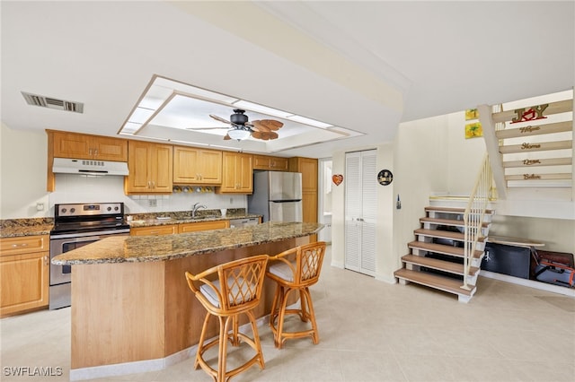 27771 Hacienda E Blvd Unit 223A, Bonita Springs, FL 34135 - kitchen featuring appliances with stainless steel finishes, under cabinet range hood, stone countertops, a kitchen breakfast bar, and a kitchen island