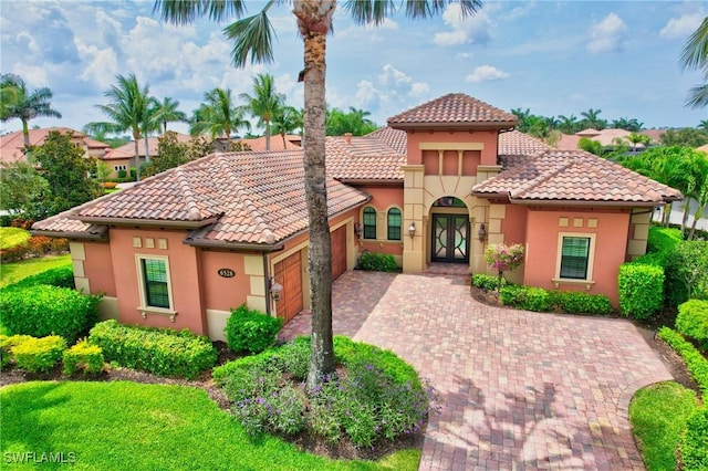 6528 Costa Cir, Naples, FL 34113 - mediterranean / spanish-style house with an attached garage, a tiled roof, french doors, and stucco siding