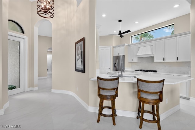 6528 Costa Cir, Naples, FL 34113 - kitchen featuring arched walkways, premium range hood, stainless steel refrigerator with ice dispenser, a breakfast bar, and light countertops