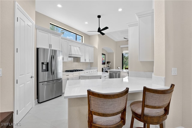 6528 Costa Cir, Naples, FL 34113 - kitchen with stainless steel appliances, ceiling fan, a peninsula, arched walkways, and a kitchen bar