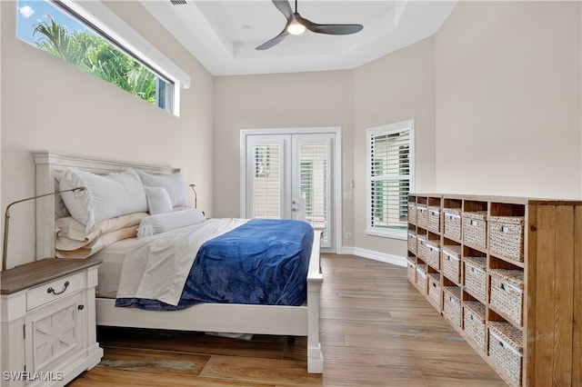 6528 Costa Cir, Naples, FL 34113 - bedroom featuring a raised ceiling, access to outside, wood finished floors, baseboards, and a towering ceiling