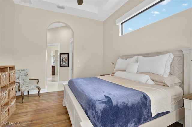 6528 Costa Cir, Naples, FL 34113 - bedroom featuring arched walkways, light wood finished floors, baseboards, and a tray ceiling