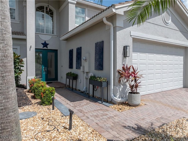 11164 Sparkleberry Dr, Fort Myers, FL 33913 - view of exterior entry with stucco siding, a garage, french doors, decorative driveway, and a tile roof