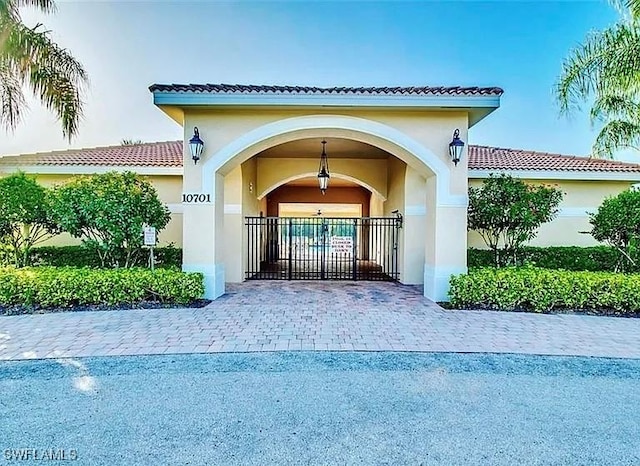 10329 Canal Brook Ln, Lehigh Acres, FL 33936 - doorway to property featuring stucco siding, a tiled roof, a gate, and decorative driveway
