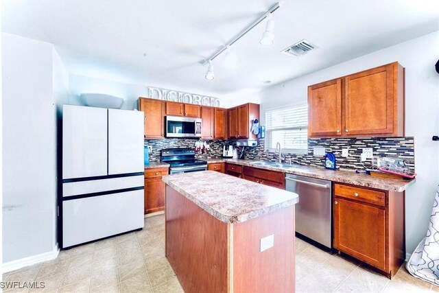 10329 Canal Brook Ln, Lehigh Acres, FL 33936 - kitchen with stainless steel appliances, a sink, a kitchen island, backsplash, and brown cabinets
