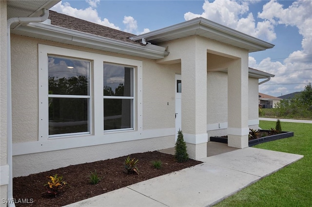 314 Pennfield St, Lehigh Acres, FL 33974 - view of exterior entry featuring stucco siding, a lawn, and a patio area