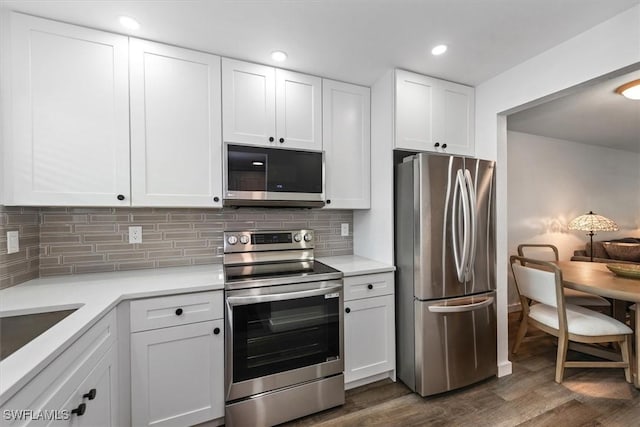 499 Forest Lakes Blvd Unit 306, Naples, FL 34105 - kitchen with appliances with stainless steel finishes, white cabinets, light countertops, dark wood-style floors, and tasteful backsplash