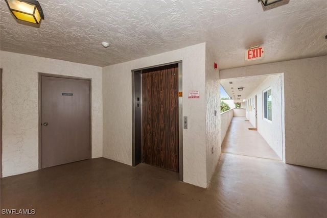 499 Forest Lakes Blvd Unit 306, Naples, FL 34105 - hallway with a textured wall, elevator, finished concrete floors, and a textured ceiling
