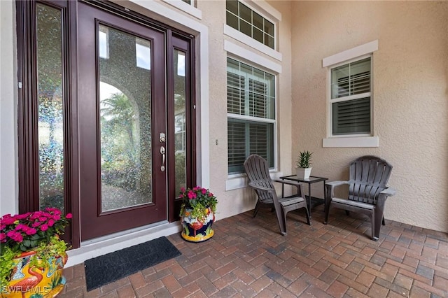 10521 Azzurra Dr, Fort Myers, FL 33913 - property entrance with stucco siding, a patio area, and outdoor dining space