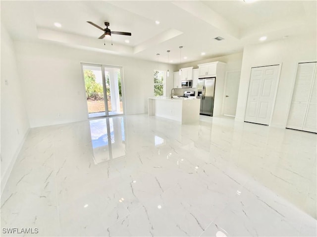 2710 21st St W, Lehigh Acres, FL 33971 - unfurnished living room with light marble finish floors, a raised ceiling, a ceiling fan, recessed lighting, and baseboards