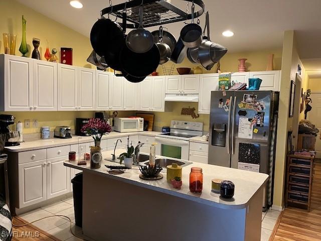 4767/4765 22nd St SW, Lehigh Acres, FL 33973 - kitchen with white appliances, under cabinet range hood, white cabinets, light tile patterned floors, and recessed lighting