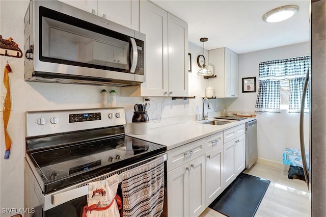 2153 Twin Brooks Rd, North Fort Myers, FL 33917 - kitchen featuring appliances with stainless steel finishes, a sink, light countertops, white cabinetry, and hanging light fixtures
