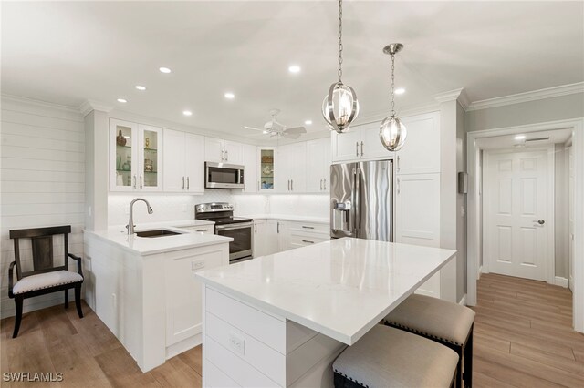 1080 S Collier Blvd Unit 103, Marco Island, FL 34145 - kitchen featuring appliances with stainless steel finishes, a sink, recessed lighting, a breakfast bar area, and light wood finished floors