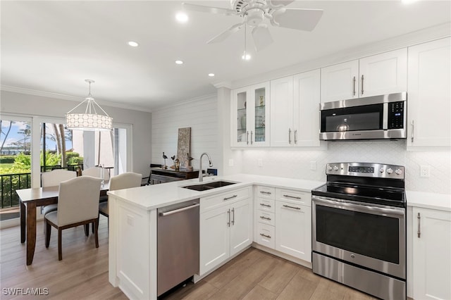 1080 S Collier Blvd Unit 103, Marco Island, FL 34145 - kitchen with stainless steel appliances, a sink, a peninsula, white cabinets, and backsplash