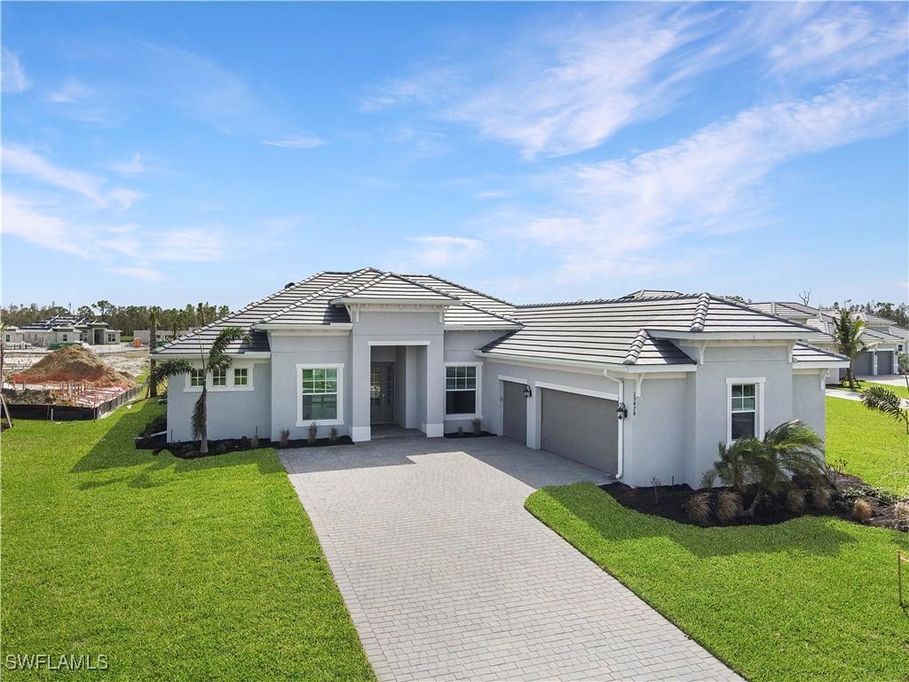 15478 Hackberry Ct, Punta Gorda, FL 33955 - prairie-style house featuring an attached garage, decorative driveway, a front lawn, and stucco siding