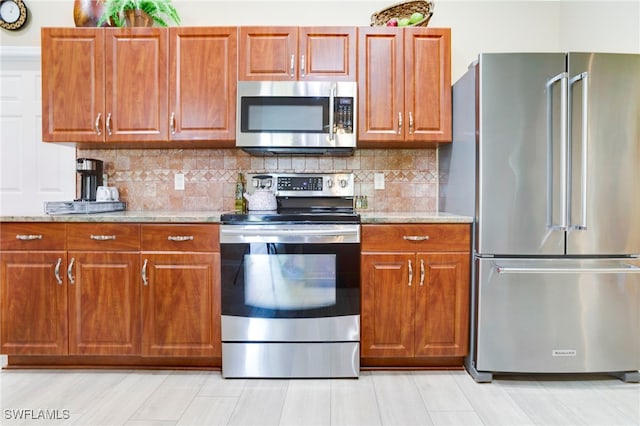 516 SE 14th Ter, Cape Coral, FL 33990 - kitchen featuring appliances with stainless steel finishes, light stone counters, brown cabinetry, and tasteful backsplash