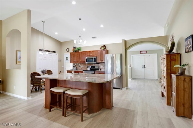 516 SE 14th Ter, Cape Coral, FL 33990 - kitchen featuring stainless steel appliances, a sink, high vaulted ceiling, light wood-style flooring, and backsplash