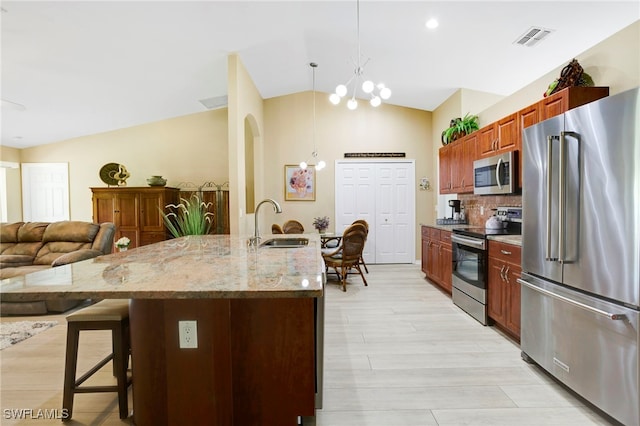 516 SE 14th Ter, Cape Coral, FL 33990 - kitchen featuring appliances with stainless steel finishes, a sink, vaulted ceiling, a kitchen bar, and backsplash