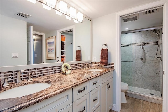 3443 Gulf Shore Blvd N Unit 409, Naples, FL 34103 - full bath with toilet, double vanity, wood finished floors, a stall shower, and decorative backsplash