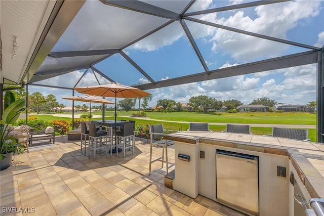 13461 Bridgeford Ave, Bonita Springs, FL 34135 - view of patio with exterior kitchen, outdoor dining space, glass enclosure, and golf course view