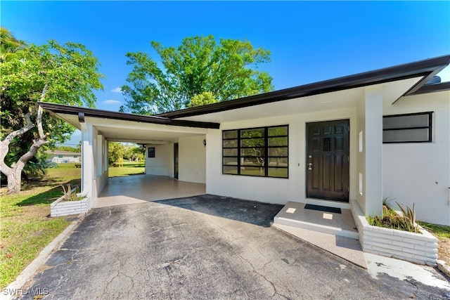 4101 Rainbow Dr, Fort Myers, FL 33916 - property entrance featuring stucco siding, asphalt driveway, and an attached carport