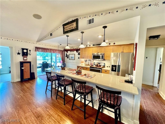 40 Ortona St, Lehigh Acres, FL 33936 - kitchen featuring appliances with stainless steel finishes, vaulted ceiling, a breakfast bar area, light countertops, and wood finished floors