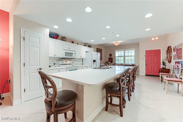10800 Palazzo Way Unit 204, Fort Myers, FL 33913 - kitchen with white appliances, a sink, a breakfast bar, a kitchen island with sink, and light countertops