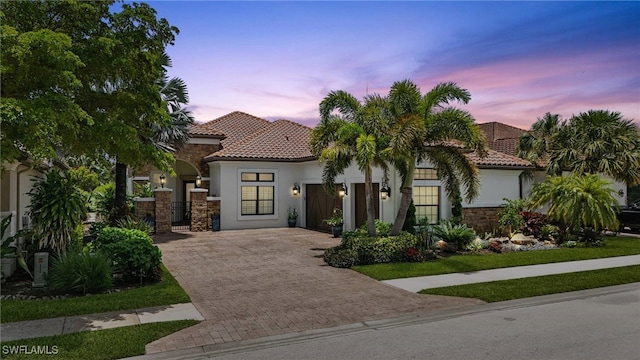 8836 Savona Ct, Naples, FL 34119 - mediterranean / spanish home featuring decorative driveway, a tile roof, stucco siding, and stone siding