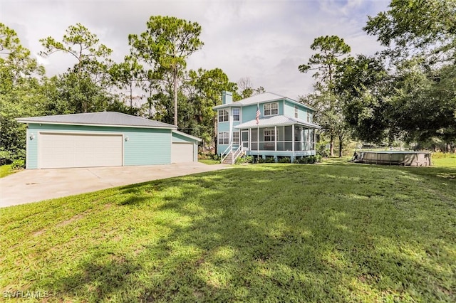 20433 Fern Cir, North Fort Myers, FL 33917 - view of grassy yard with a sunroom, a garage, an outdoor structure, and view of wooded area