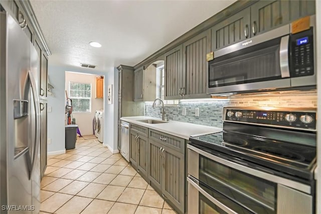 20433 Fern Cir, North Fort Myers, FL 33917 - kitchen with stainless steel appliances, backsplash, light tile patterned floors, light countertops, and washing machine and dryer
